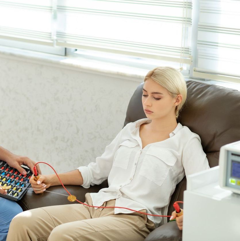 Junge Frau sitzt auf Sessel und mach eine Bioresonanztherapie